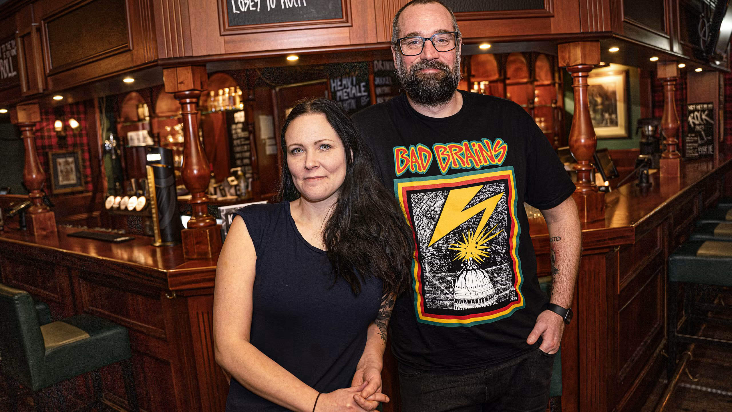Ägarparet Tessan och Robban i LochNess Pub med den välfyllda bardisken i bakgrunden.